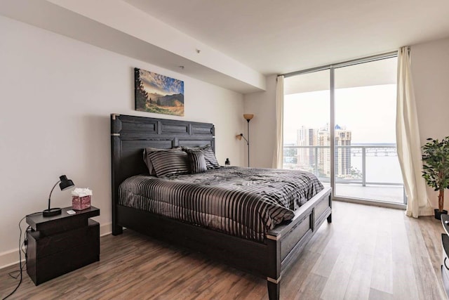 bedroom featuring access to exterior, wood-type flooring, and floor to ceiling windows