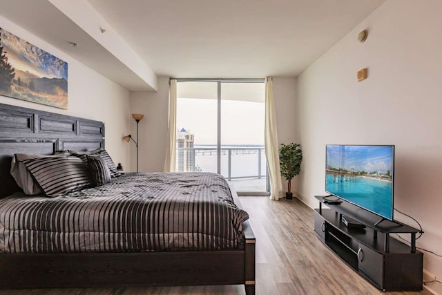 bedroom featuring expansive windows, access to outside, and light wood-type flooring