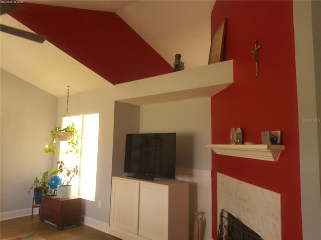 living room with a tiled fireplace, hardwood / wood-style flooring, and lofted ceiling