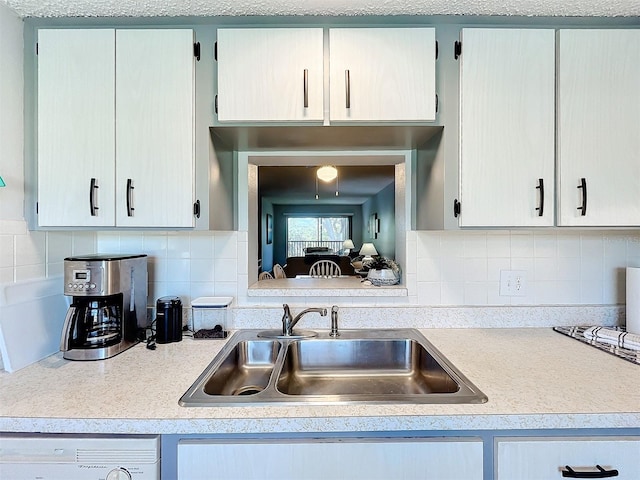 kitchen with a textured ceiling, sink, washer / clothes dryer, and tasteful backsplash