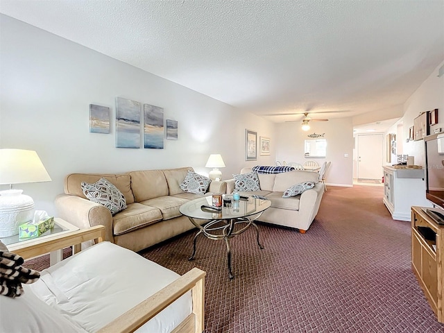 living room with a textured ceiling, carpet floors, and ceiling fan