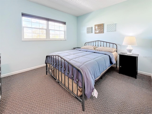 bedroom featuring dark colored carpet and a textured ceiling