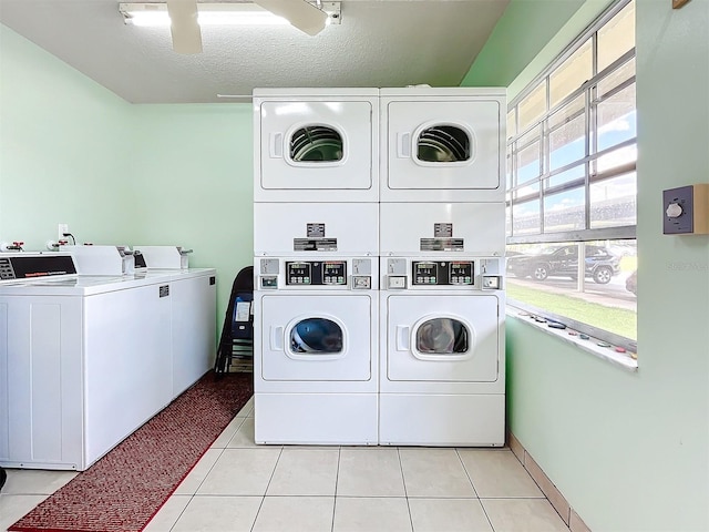 laundry area featuring washing machine and clothes dryer, light tile patterned flooring, a textured ceiling, and stacked washer / drying machine