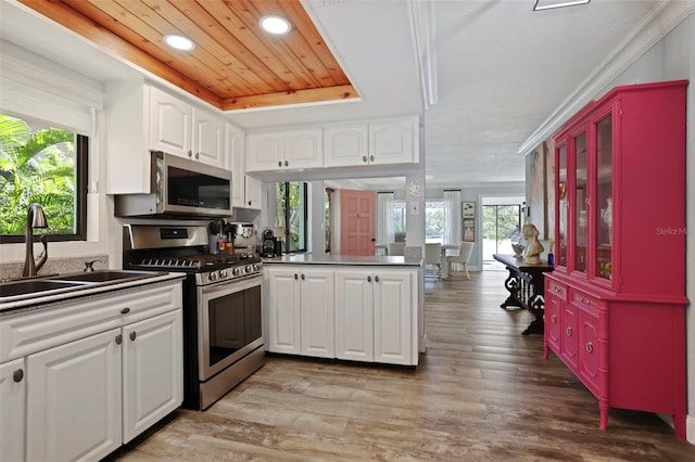 kitchen featuring appliances with stainless steel finishes, sink, kitchen peninsula, light hardwood / wood-style floors, and white cabinets