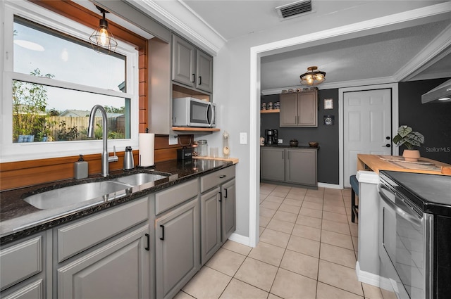 kitchen with sink, gray cabinetry, crown molding, hanging light fixtures, and light tile patterned floors