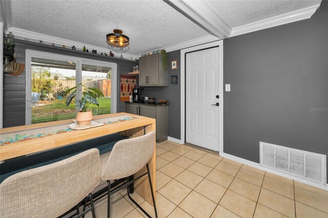 dining room with light tile patterned floors, crown molding, and a textured ceiling