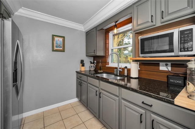 kitchen with sink, gray cabinetry, light tile patterned floors, ornamental molding, and appliances with stainless steel finishes