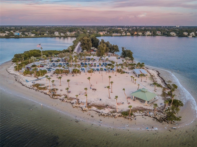 aerial view at dusk with a view of the beach and a water view