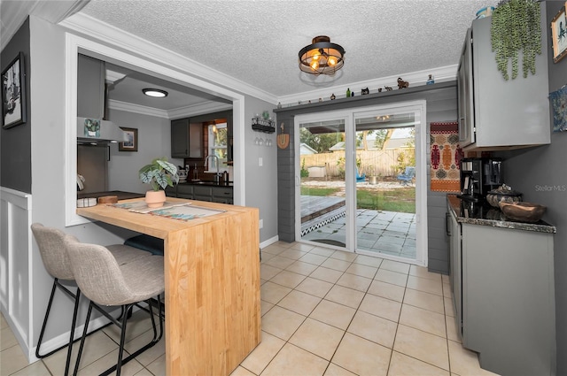 kitchen featuring ornamental molding, sink, a textured ceiling, and light tile patterned floors