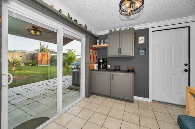 kitchen featuring ornamental molding, gray cabinets, a textured ceiling, and light tile patterned floors