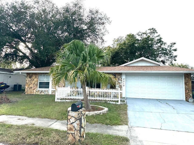 ranch-style house featuring central AC unit, a garage, and a front yard