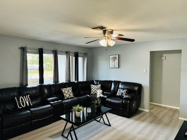 living room featuring ceiling fan, a textured ceiling, and light hardwood / wood-style flooring