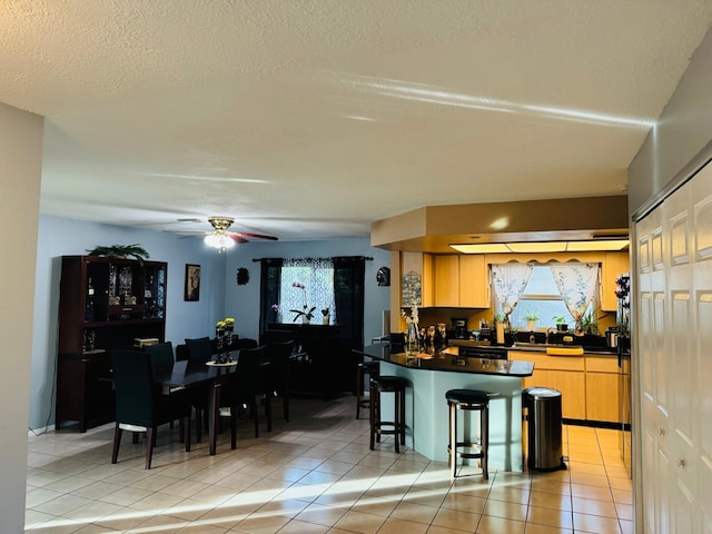 kitchen featuring light brown cabinets, a kitchen breakfast bar, light tile patterned flooring, and ceiling fan