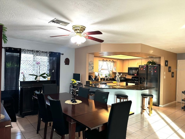 dining room featuring a textured ceiling, ceiling fan, and light tile patterned floors