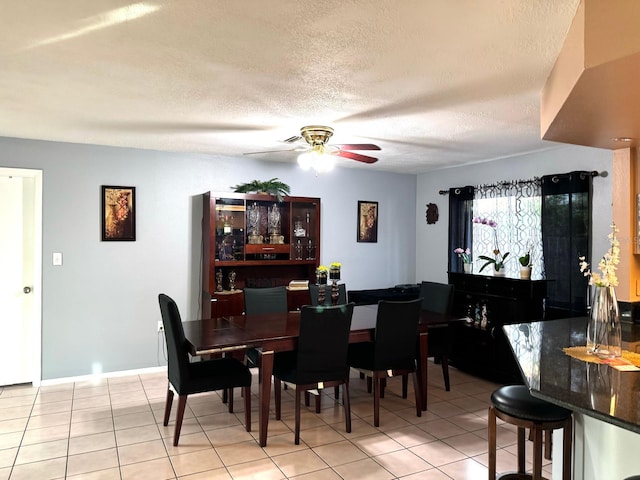 dining area with a textured ceiling, ceiling fan, and light tile patterned flooring