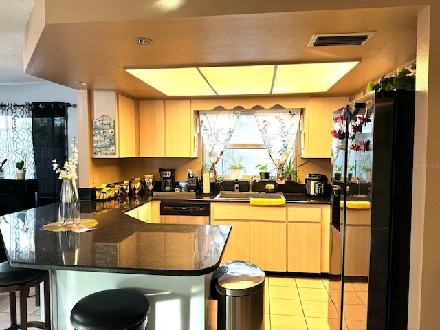 kitchen with light tile patterned flooring, sink, a breakfast bar, kitchen peninsula, and light brown cabinetry