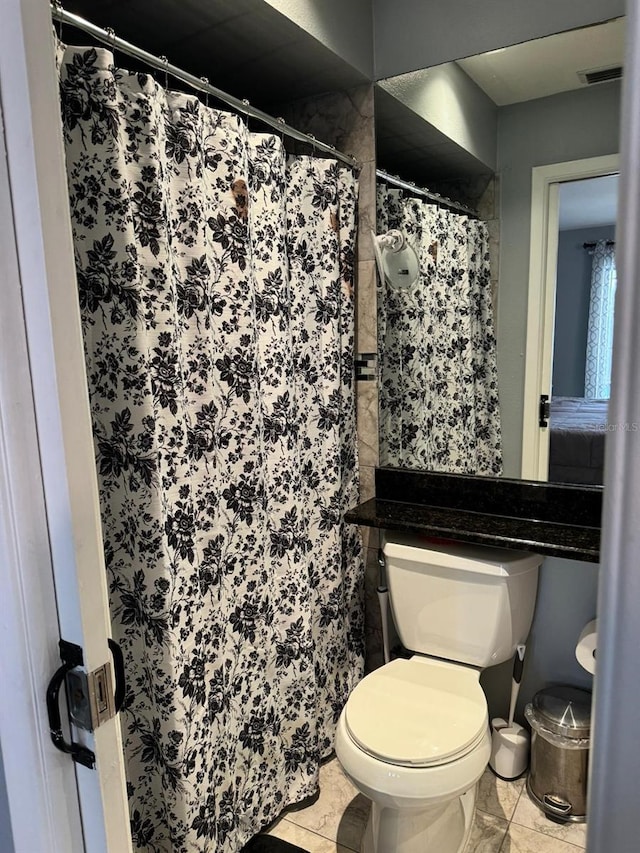 bathroom featuring toilet, tile patterned floors, and curtained shower