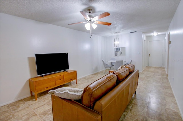 living room featuring ceiling fan and a textured ceiling