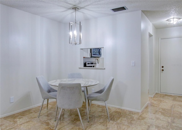 dining room featuring a textured ceiling and an inviting chandelier