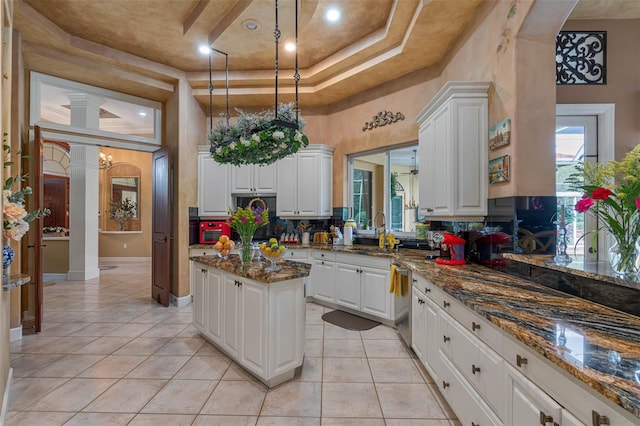 kitchen with white cabinetry, dark stone countertops, a center island, and backsplash