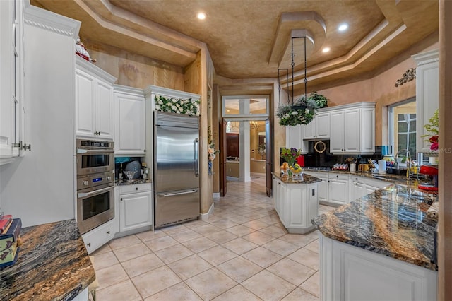 kitchen featuring sink, appliances with stainless steel finishes, a tray ceiling, and white cabinets