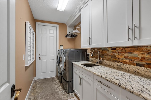 laundry room with a textured ceiling, cabinets, sink, and separate washer and dryer