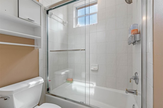 bathroom with toilet and shower / bath combination with glass door