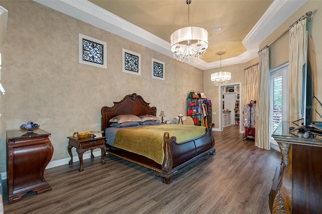 bedroom featuring ornamental molding, dark wood-type flooring, a tray ceiling, and a chandelier