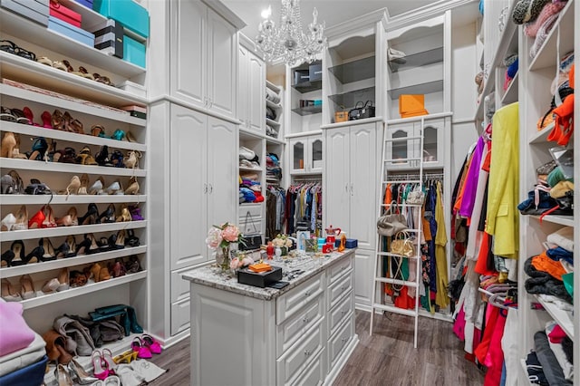 spacious closet with a notable chandelier and dark hardwood / wood-style floors