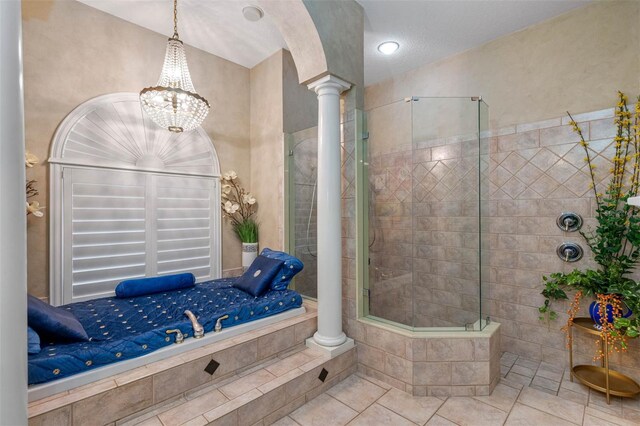 bathroom featuring a tile shower, a notable chandelier, tile patterned floors, and ornate columns