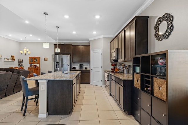 kitchen with light stone countertops, appliances with stainless steel finishes, pendant lighting, a breakfast bar area, and a center island with sink