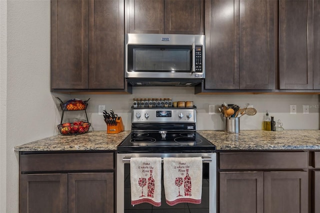 kitchen featuring appliances with stainless steel finishes, dark brown cabinetry, and light stone countertops