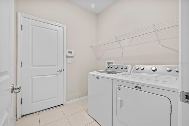 laundry room with washer and clothes dryer and light tile patterned floors