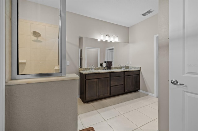 bathroom featuring vanity, tile patterned flooring, and tiled shower