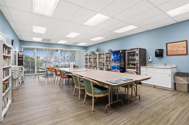 dining space with light hardwood / wood-style flooring, beverage cooler, and a paneled ceiling