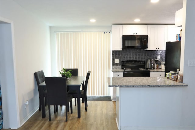 kitchen with black appliances, backsplash, light stone countertops, white cabinetry, and light hardwood / wood-style flooring