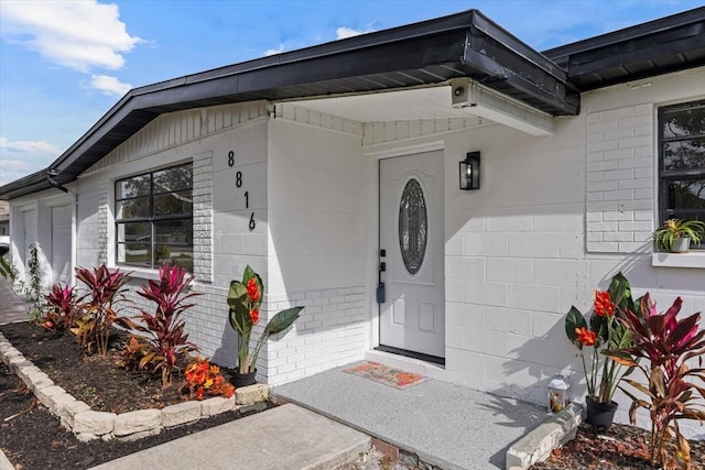 doorway to property featuring concrete block siding and brick siding