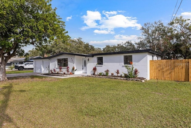 ranch-style house with concrete block siding, an attached garage, a front yard, fence, and driveway