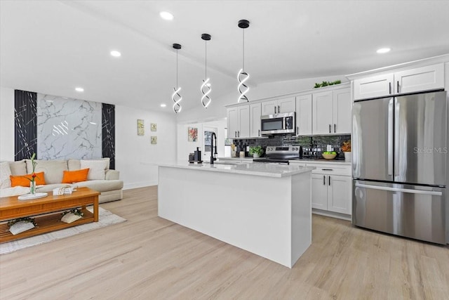 kitchen featuring vaulted ceiling, stainless steel appliances, white cabinetry, and an island with sink