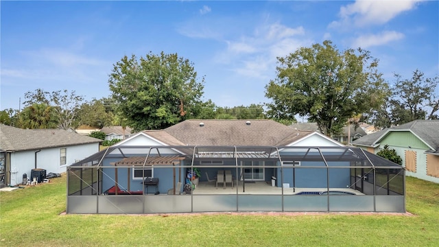 rear view of house with a lawn, a patio area, and glass enclosure