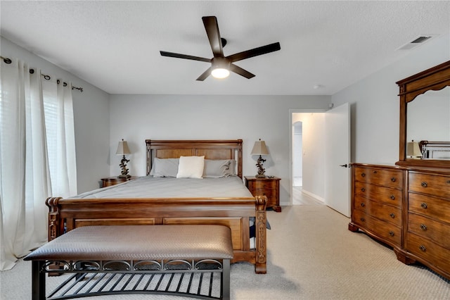 bedroom with ceiling fan, a textured ceiling, and light colored carpet