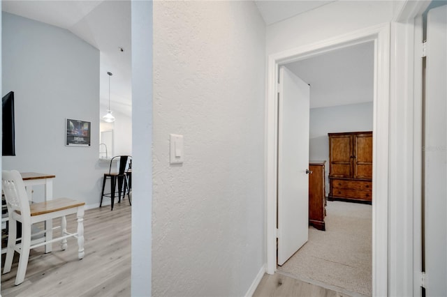 hall featuring light hardwood / wood-style flooring and vaulted ceiling