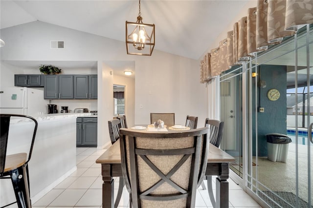 tiled dining area featuring vaulted ceiling and a notable chandelier