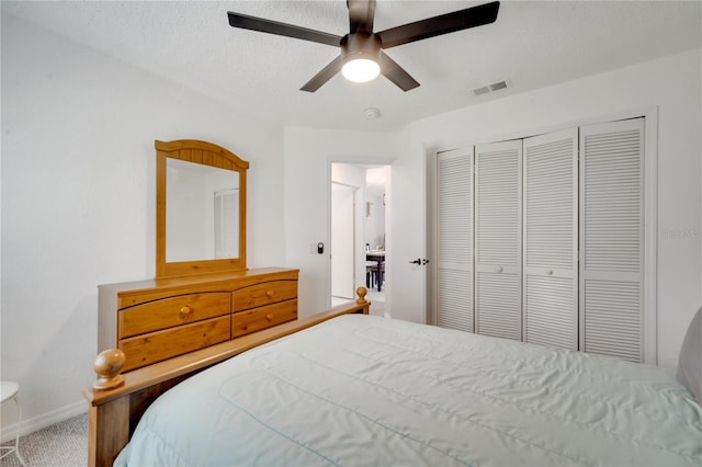 bedroom with a closet, ceiling fan, carpet flooring, and a textured ceiling