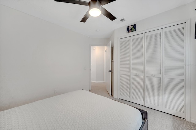 bedroom with a closet, ceiling fan, and light colored carpet