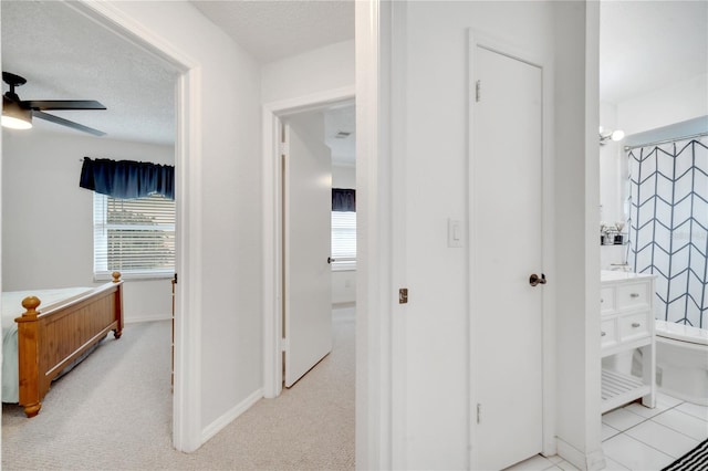 hall with a textured ceiling and light colored carpet