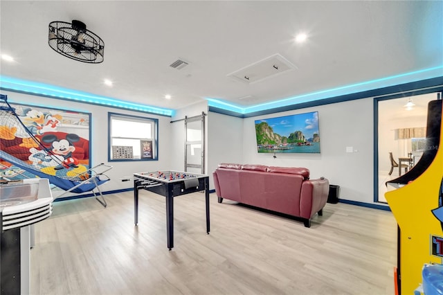 recreation room featuring a barn door and light hardwood / wood-style floors