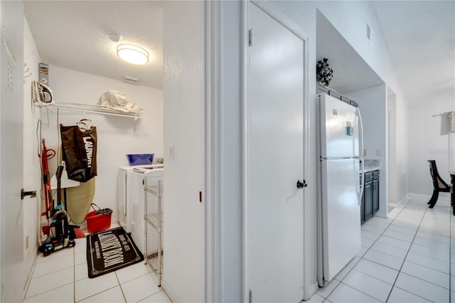 interior space featuring independent washer and dryer, a textured ceiling, and light tile patterned floors