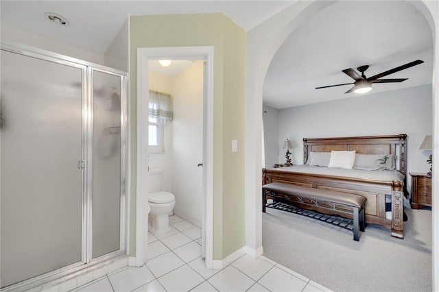 tiled bedroom featuring ceiling fan and ensuite bath