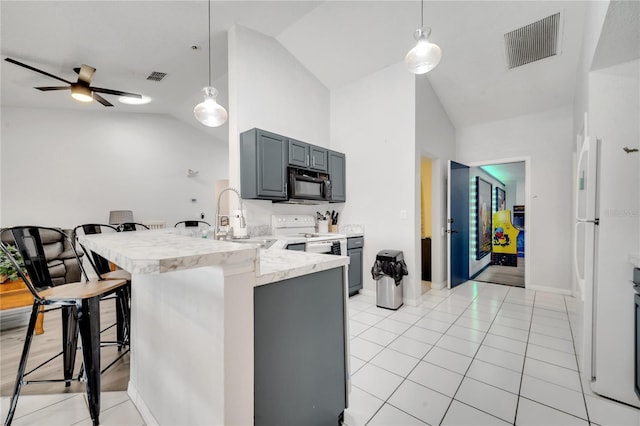 kitchen with white appliances, gray cabinetry, kitchen peninsula, lofted ceiling, and a breakfast bar area